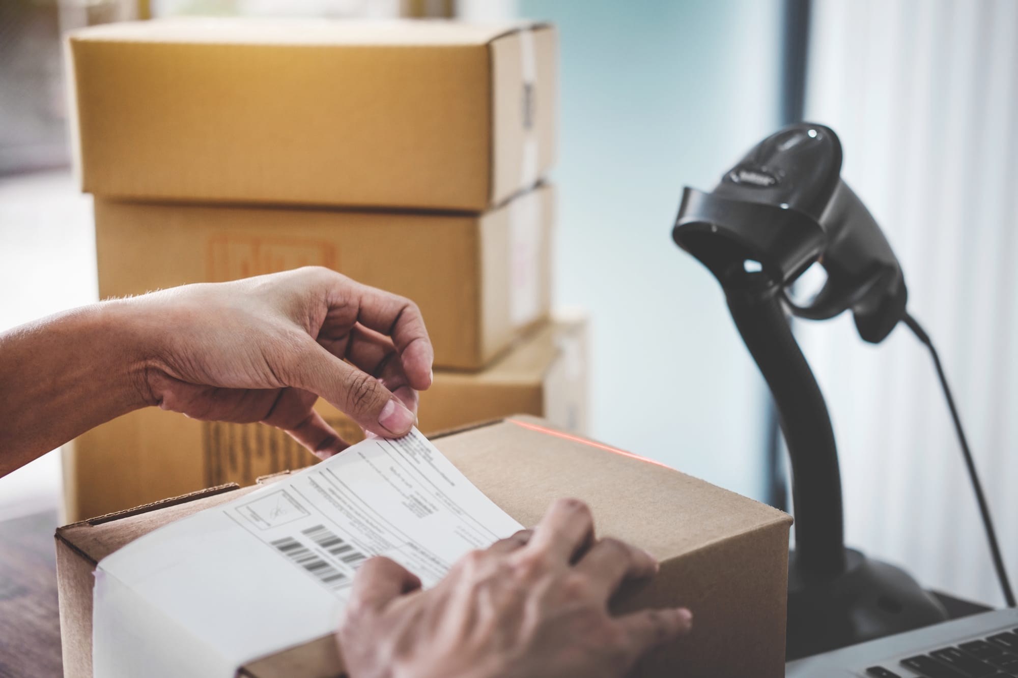 Two hands attaching a barcode label on box package