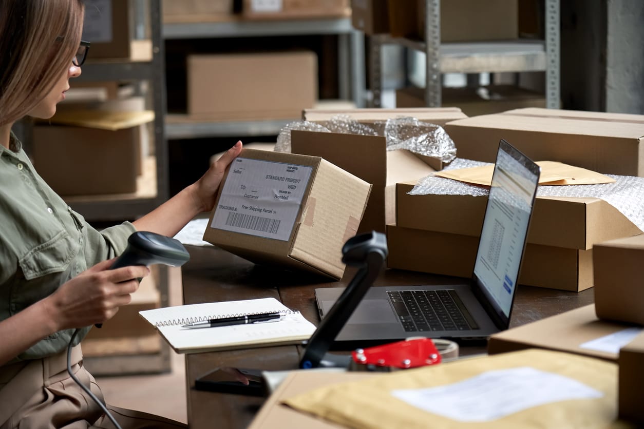 Female business owner scanning item barcodes in a storage full of boxes